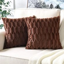 Detail of two dark brown plush pillow covers with 3D diamond texture on a sofa