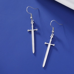 Macro detail of silver sword-shaped stainless steel earrings on a blue background