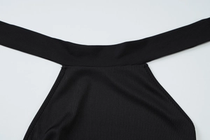 Detailed view of black ribbed knit fabric showing the halter neckline and refined stitching