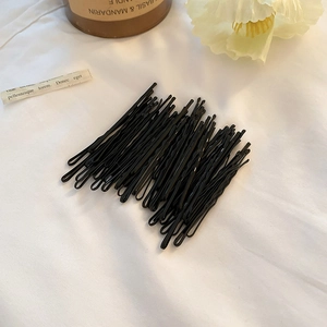 Vue détaillée de barrettes noires ondulées sur un fond textile blanc doux