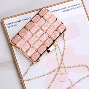 Close-up of pink acrylic evening clutch with gold metal frame and chain strap