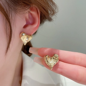 Boucles d'oreilles cœur dorées avec texture martelée portée par une femme