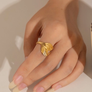 Close-up of a gold leaf-shaped open ring with intricate cutout details on a woman's finger