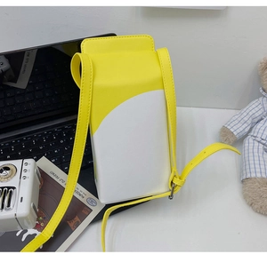 Detail view of the yellow milk carton crossbody bag shown in a cozy lifestyle setting
