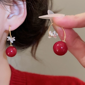 Macro shot of red resin bead earrings with crystal butterfly detail and gold plated hooks