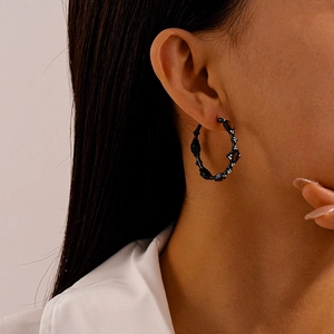 Close-up of black geometric C-shape hoop earrings worn by a model for a stylish look