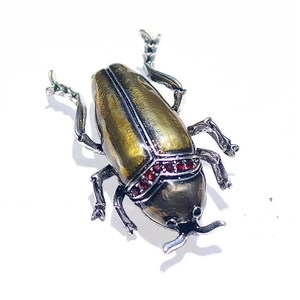 Vintage beetle insect brooch in antique gold and silver with red crystals on white background