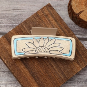 Detail of sunflower pattern on rectangular beige hair claw clip with blue border
