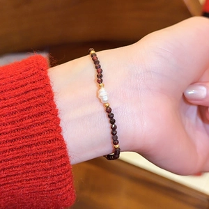 Nahaufnahme eines roten Achat-Perlenarmbands mit einer Barockperle am Handgelenk.