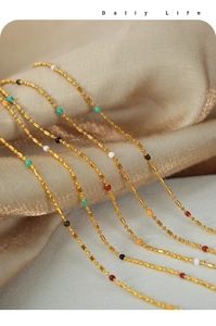 Close-up of golden titanium necklaces with colorful beads on soft silk background