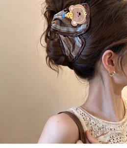 Detailed side view of a brown plaid hair claw clip with a cute cartoon bear on hair