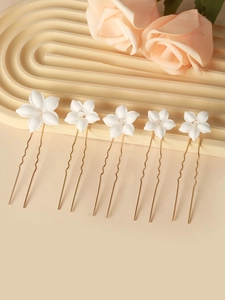 Detail showing five white ceramic bridal flower hair pins with crystals and gold U-pins