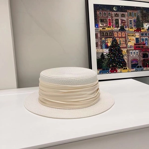 Detail of white boater hat featuring elegant champagne silk ribbon and straw texture
