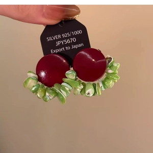 Close-up of geometric earrings with burgundy lacquer and green crushed stone beads