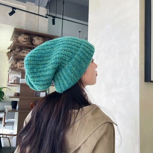 Detailed close-up showing the thick knit texture and turquoise roll-up edge of the beanie