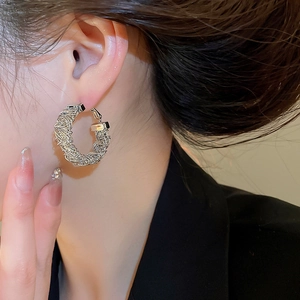 Macro shot of silver-colored woven bird nest hoop earrings with detailed metal textures