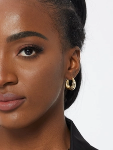Close-up of golden textured hoop earring on model showing layered stripe detail