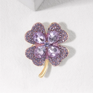 Detailed view of luxury purple crystal clover brooch with golden stem and sparkling rhinestones