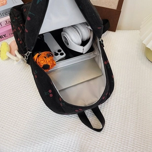 Internal view of cherry print corduroy backpack showing laptop compartment and storage capacity