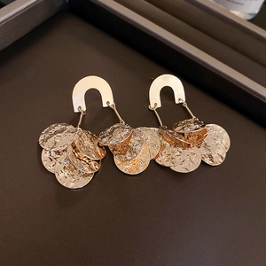 Macro view of gold U-shaped earrings featuring layered hammered metal discs with textured finish