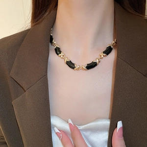 Gros plan du collier vintage avec maillons croisés dorés et émail noir sur mannequin