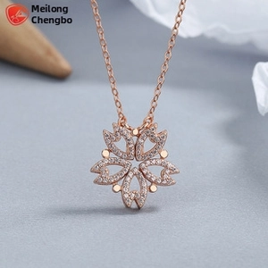 Vue macro du pendentif fleur en or rose avec pétales en cœur et zircons étincelants
