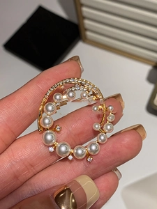 Detailed macro view of 24k gold-plated brooch featuring shimmering pearls and zircons