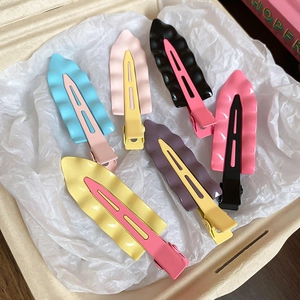 Macro shot of colorful wavy matte duckbill hair clips in a soft minimalist box