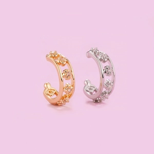 Detail showing two floral ear cuffs in gold and silver with sparkling rhinestones