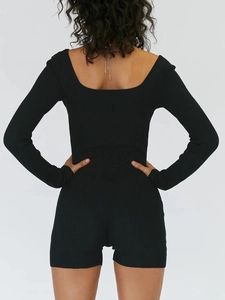 Back view of a black ribbed knit long sleeve yoga romper with a form-fitting design