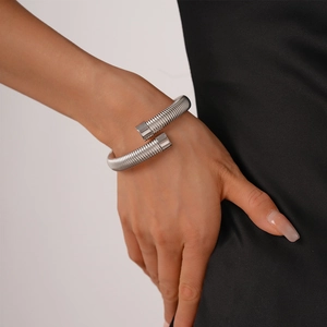 Detailed view of a silver snake-shaped stretch cuff bracelet worn on a woman's wrist