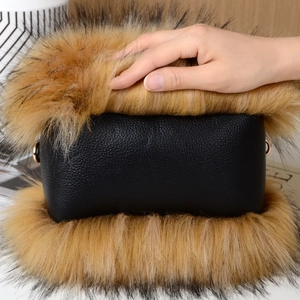 Detail of luxury black pebbled leather handbag featuring soft faux raccoon fur trim and gold rings