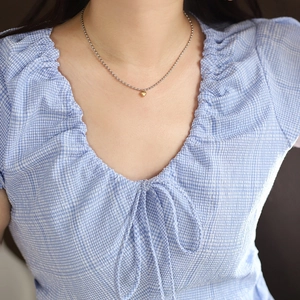 Close-up of golden heart pendant on silver bead chain worn on a neck for chic styling