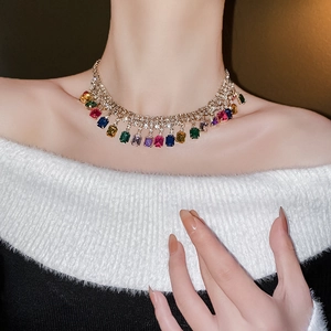 Gros plan d'un collier choker doré avec des pierres précieuses carrées colorées