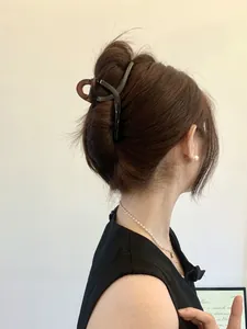 Detail of 13cm large hair claw clip securing a bun hairstyle from a back side view