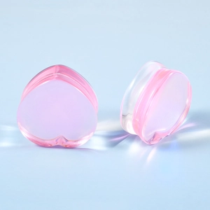 Macro detail of heart-shaped pink glass ear plugs showing polished finish and clarity