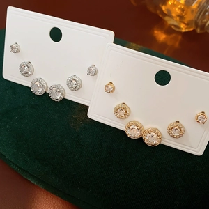 Dettaglio di set di orecchini a lobo in zirconia cubica oro e argento su carte