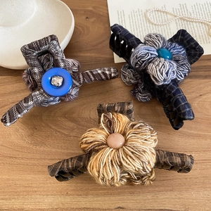 Close-up of fabric floral hair claws with plaid texture and button accents on wood