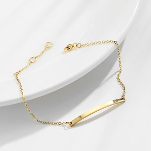 Gold-plated stainless steel rectangular bar bracelet on white ceramic plate