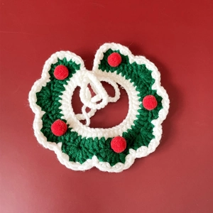 Close-up of green and white hand-knitted Christmas pet collar with red decorative pom-poms