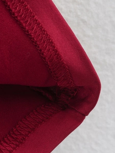 Close-up detail of red knitted fabric with precise overlock stitching and soft texture