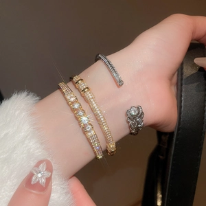 Detail of gold and silver plated bracelets with pavé zircons on woman's wrist