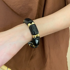 Detail of acrylic bead bracelet with black marble texture and gold metallic accents