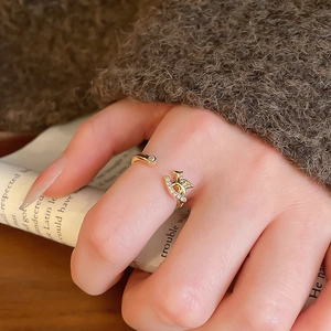 Detail of bird-shaped gold-plated ring with zircons worn on hand over a magazine