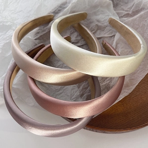 Detailed top view of four padded satin headbands in soft Morandi colors on wooden base