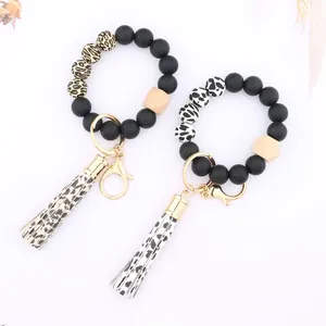 Close-up of leopard and cow print silicone bead keychains with wood accents and tassels