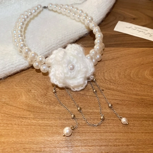Détail du collier de perles double épaisseur avec fleur en tricot et franges dorées
