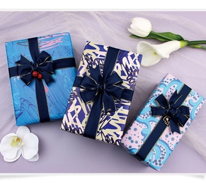 Flat lay of elegant blue gift wrapping paper sets with silk ribbons and floral accents