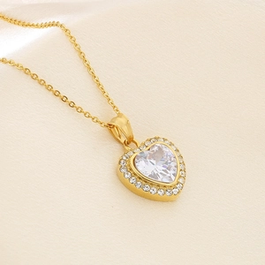 Macro detail of 18K gold heart pendant with a sparkling central gem and halo setting