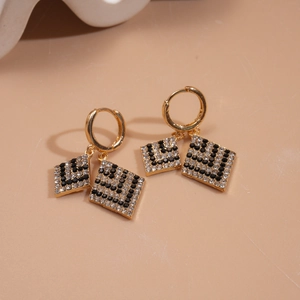 Golden geometric diamond earrings with checkered rhinestones on a warm beige background